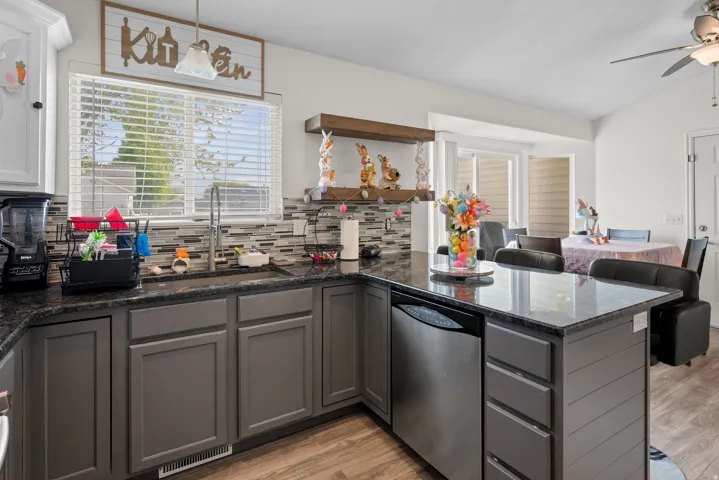 Kitchen featuring gray shaker-style cabinetry, dark granite-look countertops, and a mosaic tile backsplash