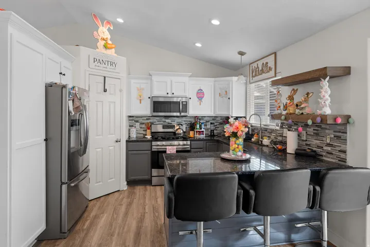 Modern kitchen featuring a breakfast bar with seating, dark granite countertops, and a full stainless steel appliance package