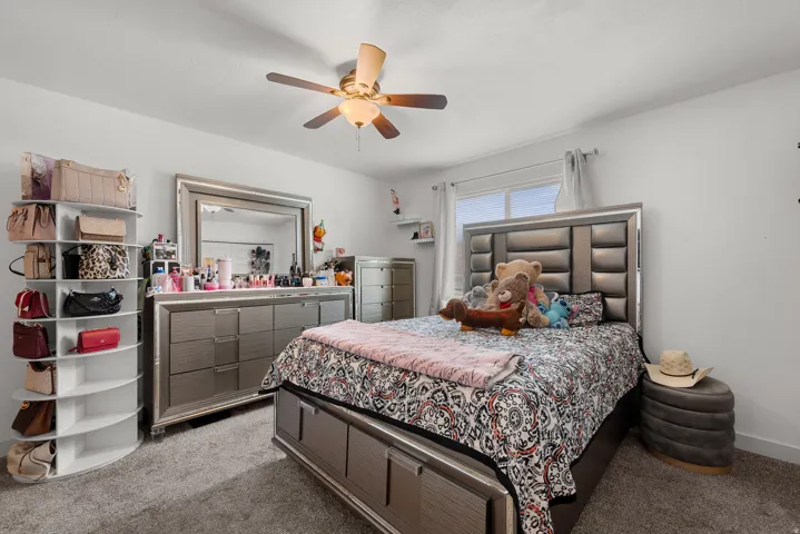 Bedroom featuring a multi-pane window, flush-mounted ceiling fan with integrated lighting, and neutral tone carpet flooring