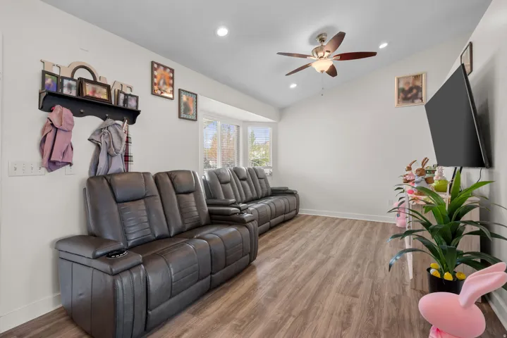 Spacious living area featuring vaulted ceilings, recessed lighting, wood-finish flooring, a ceiling fan, and bay windows
