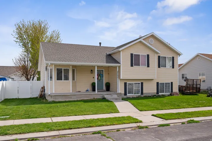 Split-level home featuring a covered front porch, light-colored siding, and dark shutters