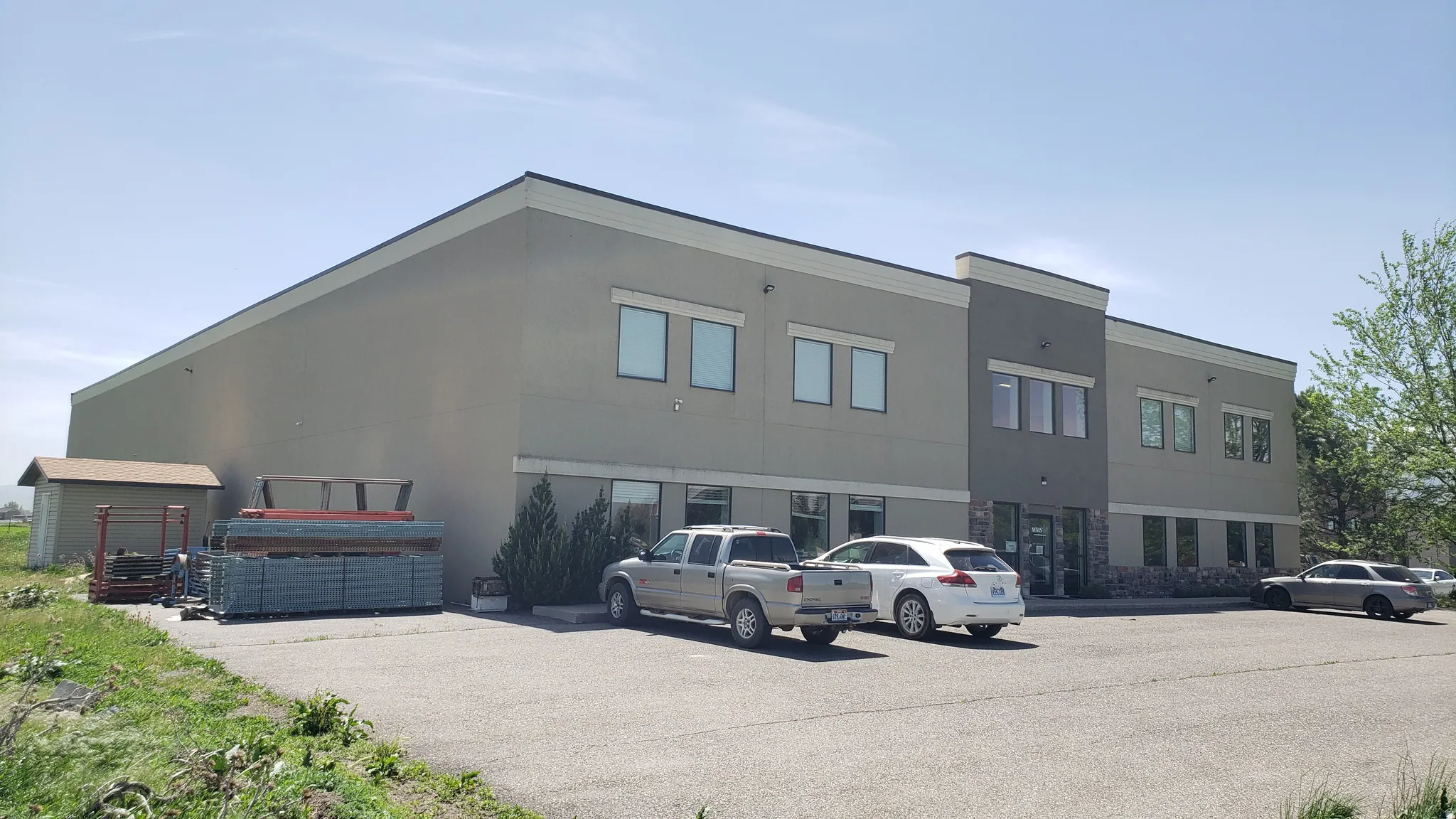 Contemporary commercial building featuring a multi-toned facade with stone veneer accents, multiple window openings, and an expansive paved parking area