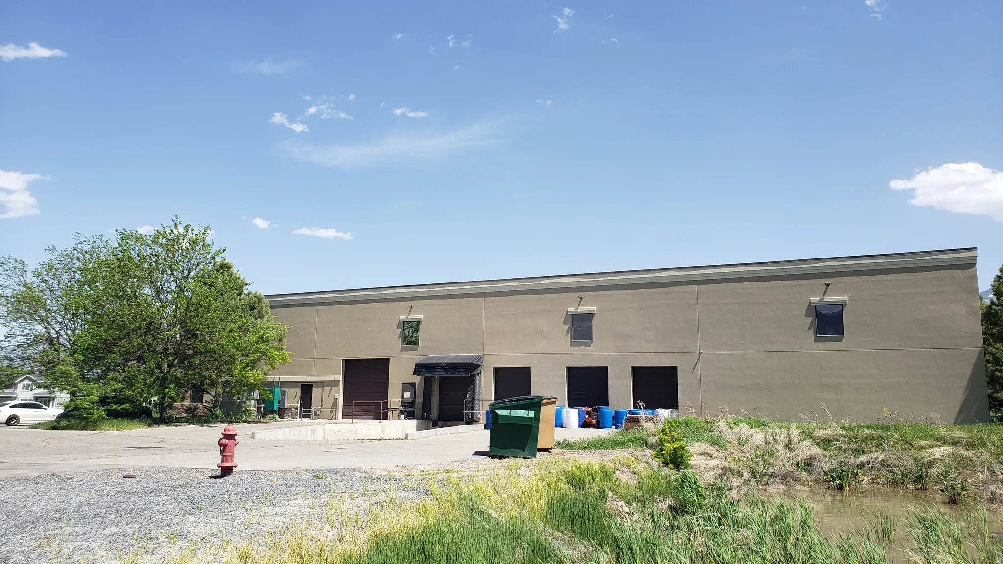 Industrial-style building featuring a light-colored stucco exterior with multiple loading dock doors