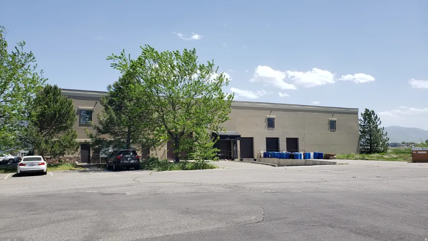 Commercial building featuring a large paved parking area, multiple roll-up doors for access, and a loading dock
