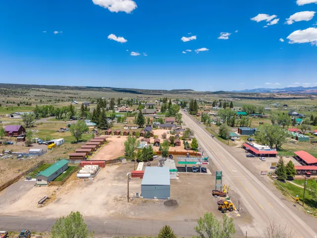 Aerial perspective of a commercial property featuring a gas station, a metal-clad building, and a motel with multiple cabins