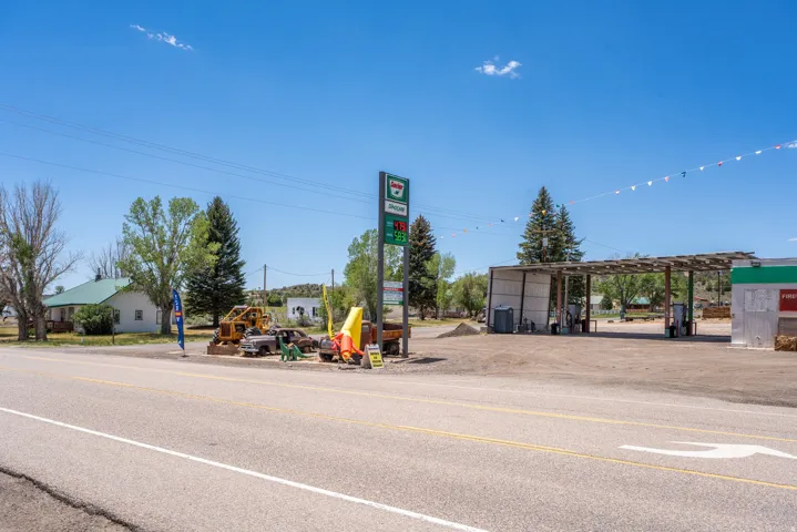 Commercial property featuring a paved forecourt, covered fuel pump area, and a prominent roadside sign