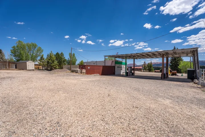 Gravel-surfaced lot featuring a multi-pump fuel station with an overhead canopy