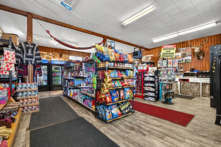 Retail interior featuring wood-finish flooring, exposed ceiling beams, and fluorescent lighting