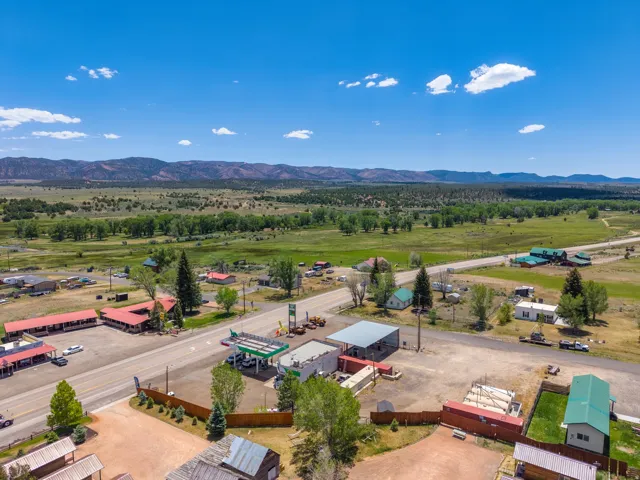 Expansive rural landscape featuring distant mountains, lush green fields, and a clear blue sky