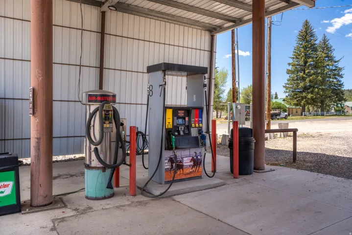 Covered fueling station featuring a fuel pump and an air/water dispenser on a concrete pad