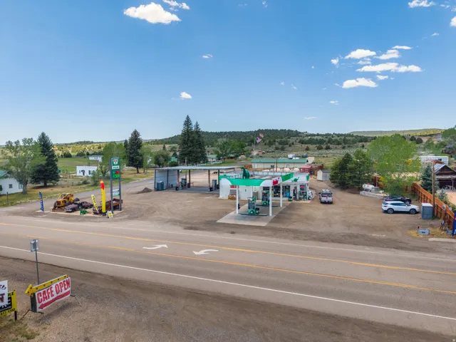 Commercial property featuring a gas station with multiple pumps, covered fueling areas, and an adjacent retail building