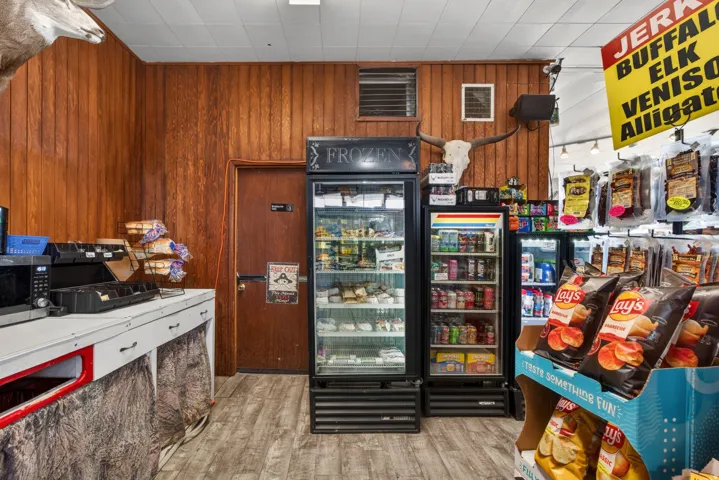 Retail interior featuring wood paneling, wood-finish flooring, two glass-door display refrigerators, and a built-in counter