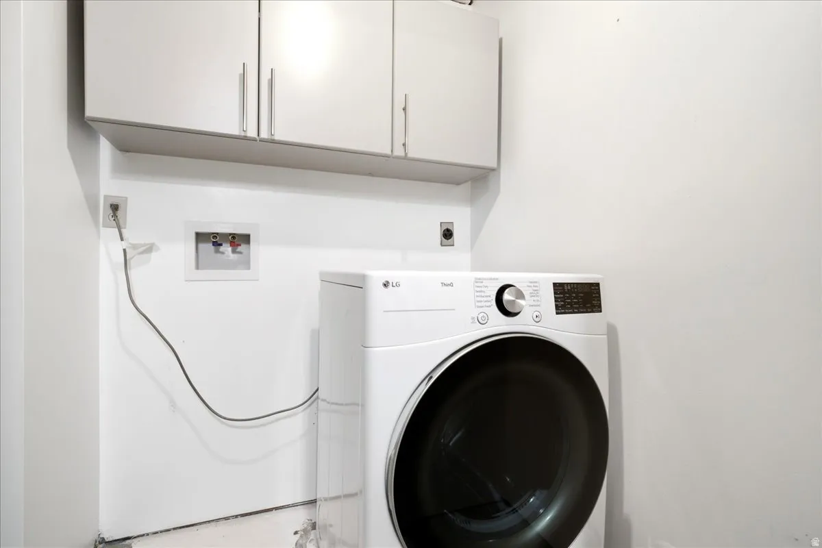 White cabinetry with brushed nickel hardware positioned above appliance hookups
