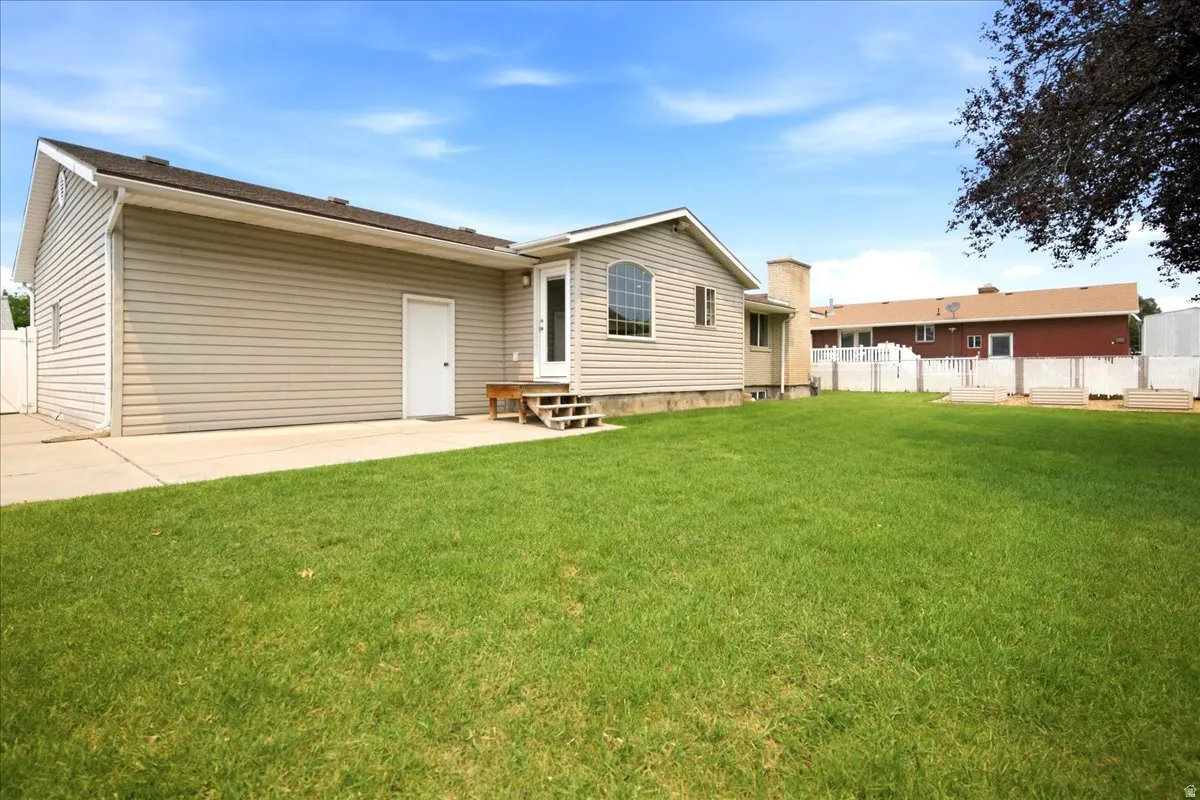 Expansive green lawn with a white privacy fence and concrete patio