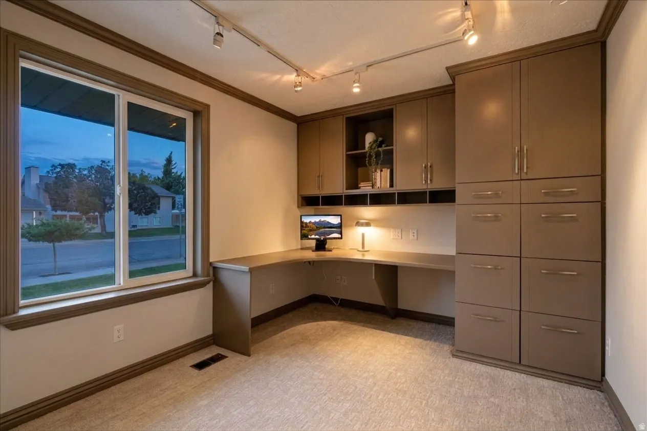 Built-in L-shaped desk with integrated storage cabinetry and track lighting