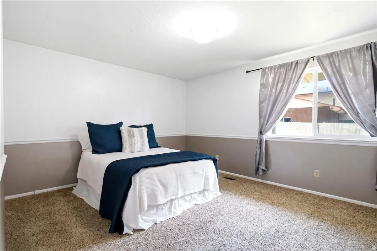 Carpeted interior master bedroom with a large window