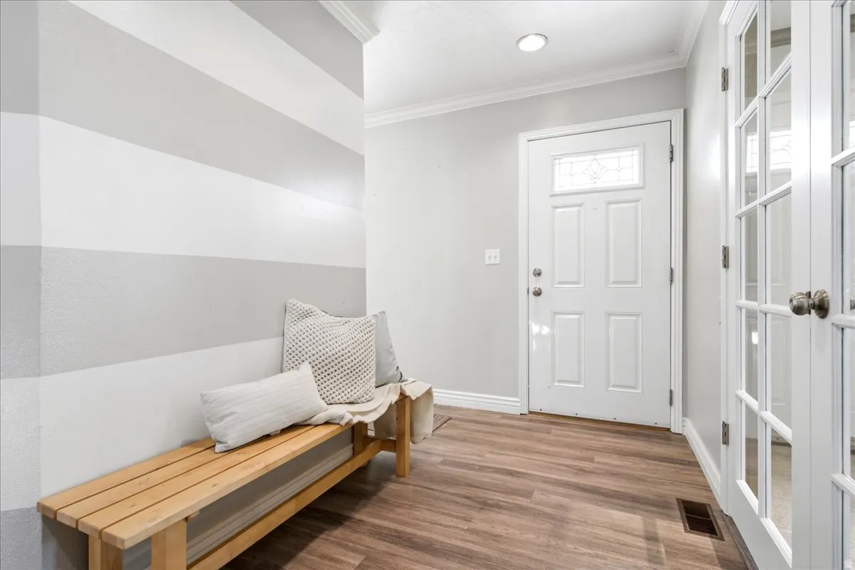 Entryway featuring wood-finish flooring, a white paneled door with decorative glass, and a neutral color palette