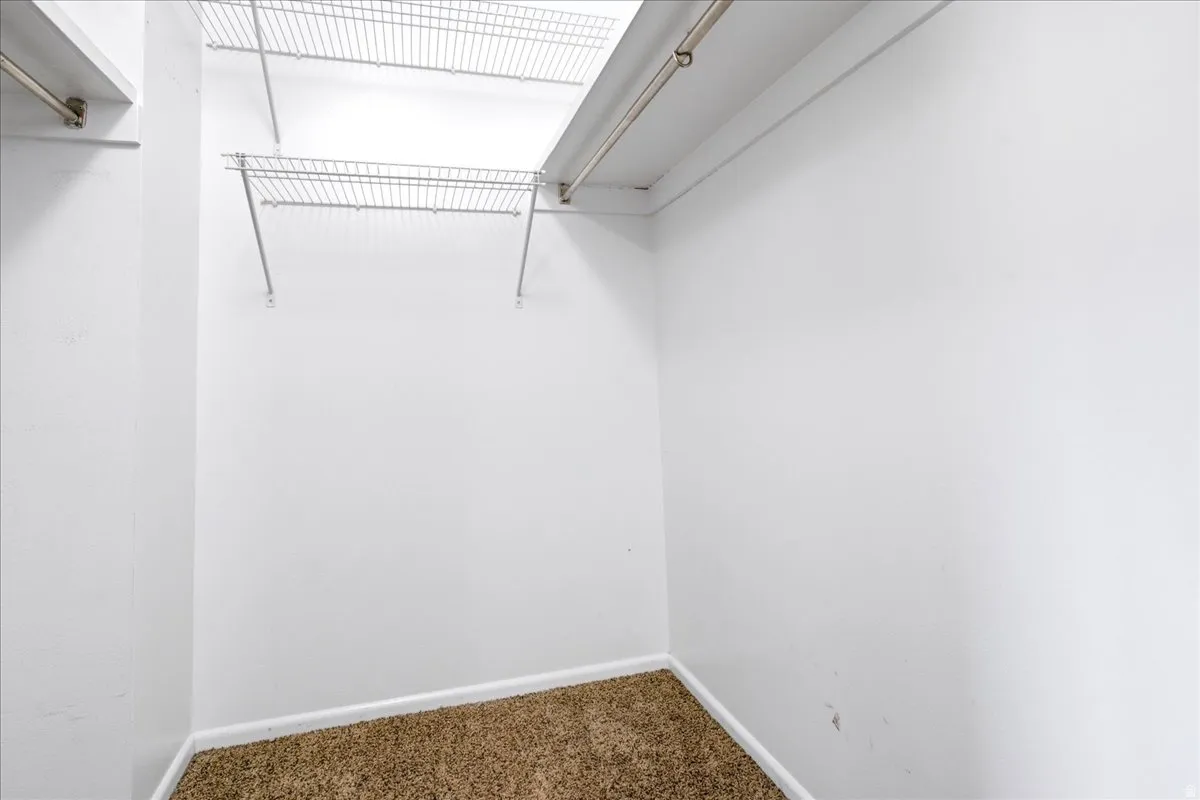 Master Bedroom Walk-in closet featuring white walls, wire shelving, and brown carpet flooring