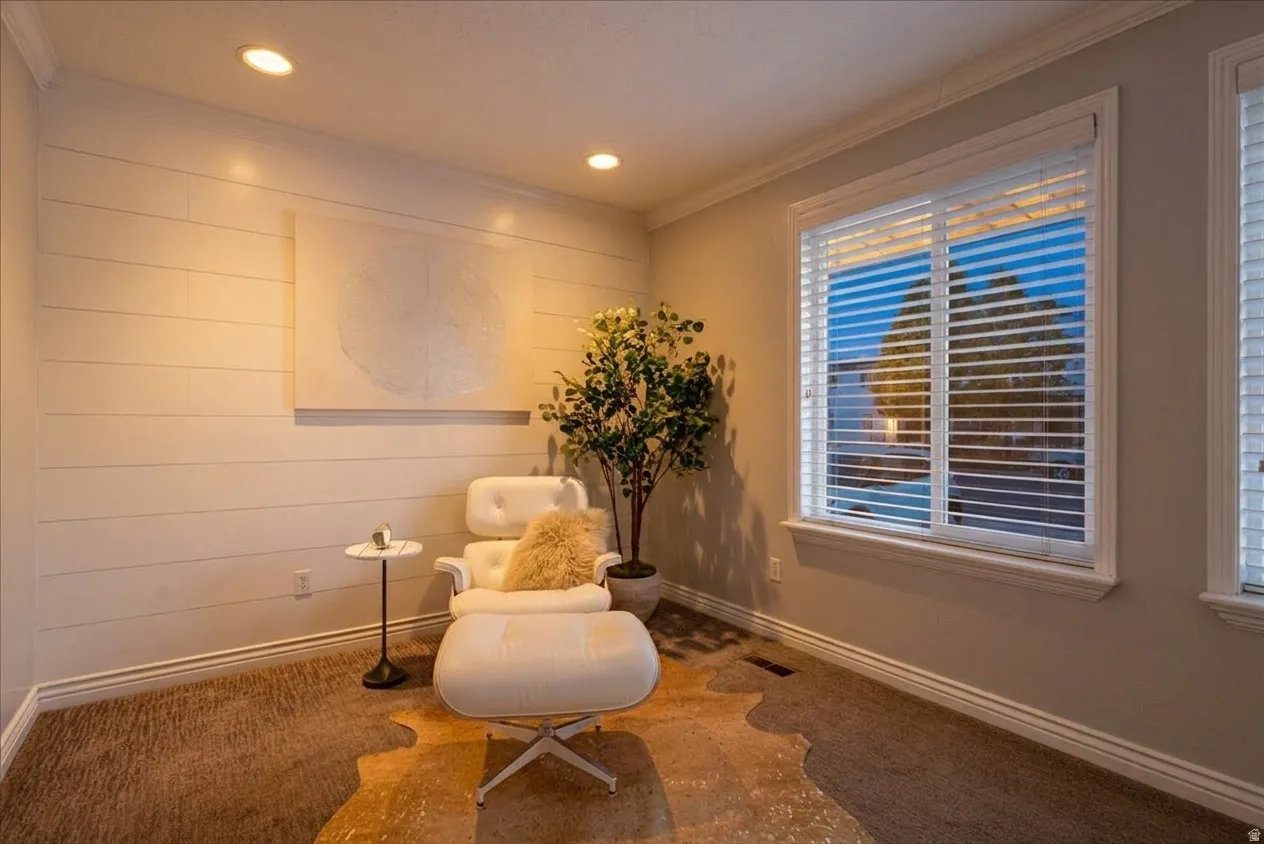 Recessed lighting illuminates a shiplap accent wall with crown molding and baseboards