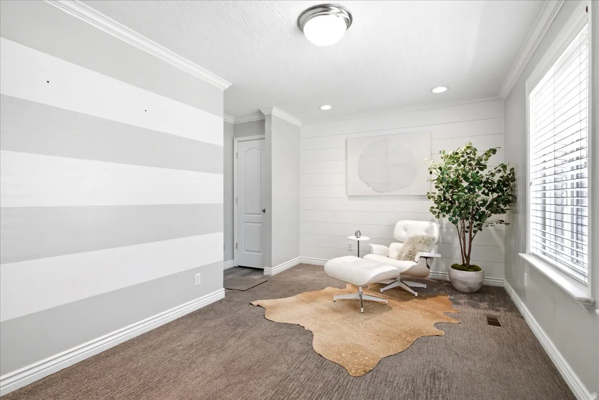 Inviting room featuring a window with blinds, recessed lighting, crown molding, and a shiplap accent wall