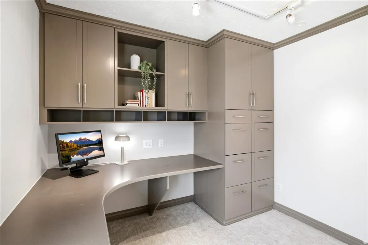 Built-in desk area featuring an L-shaped countertop, integrated cabinetry, open shelving, under-cabinet lighting, and track lighting
