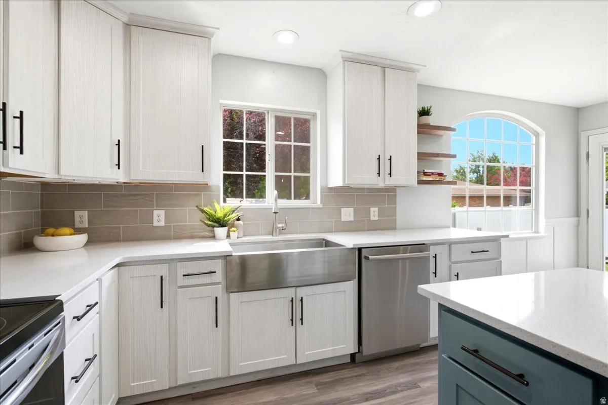 Kitchen featuring white shaker-style cabinetry, stainless steel farmhouse sink, quartz countertops, subway tile backsplash, and wood-finish flooring
