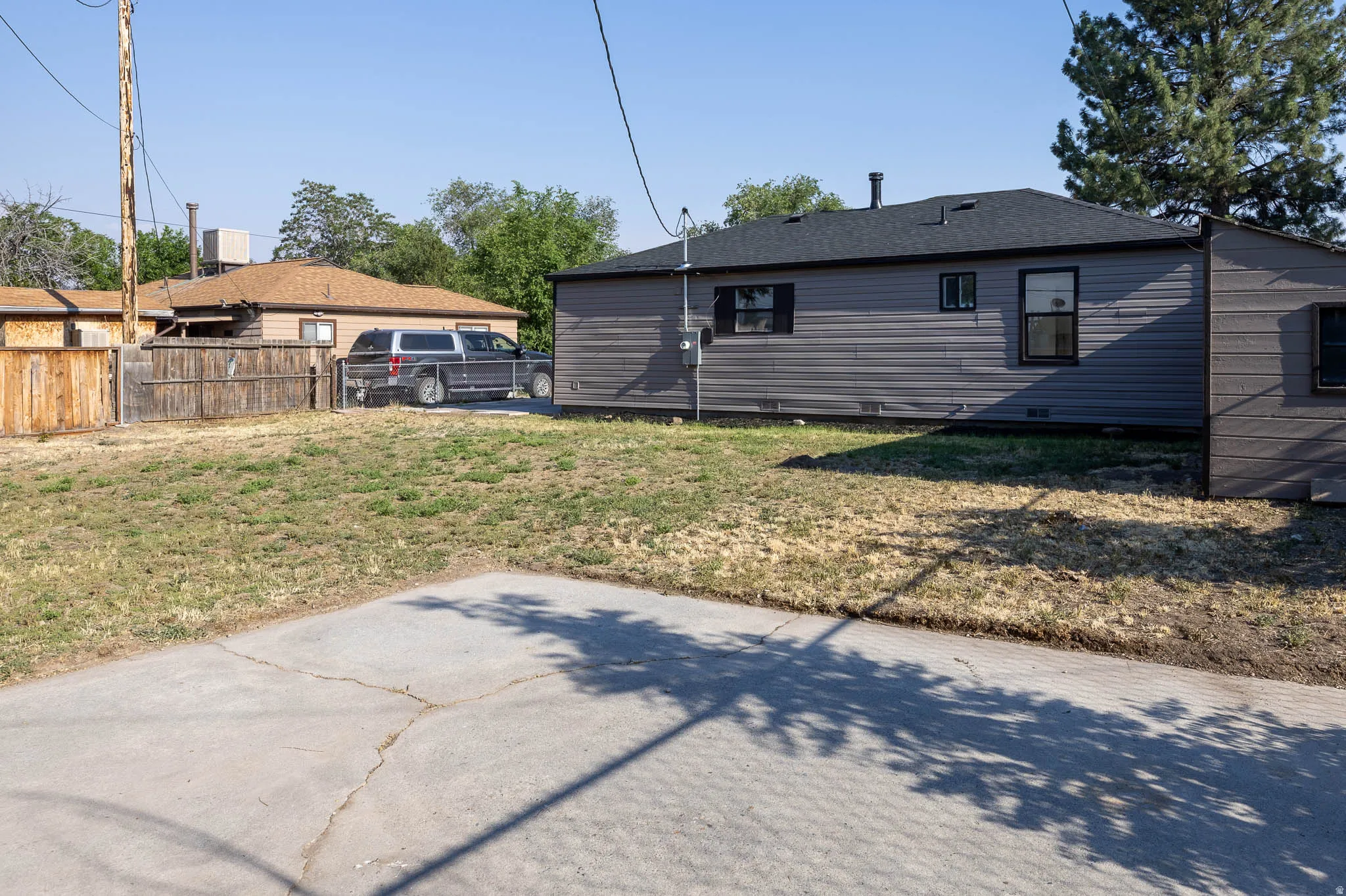 Spacious outdoor area featuring a concrete pad and a partially fenced perimeter