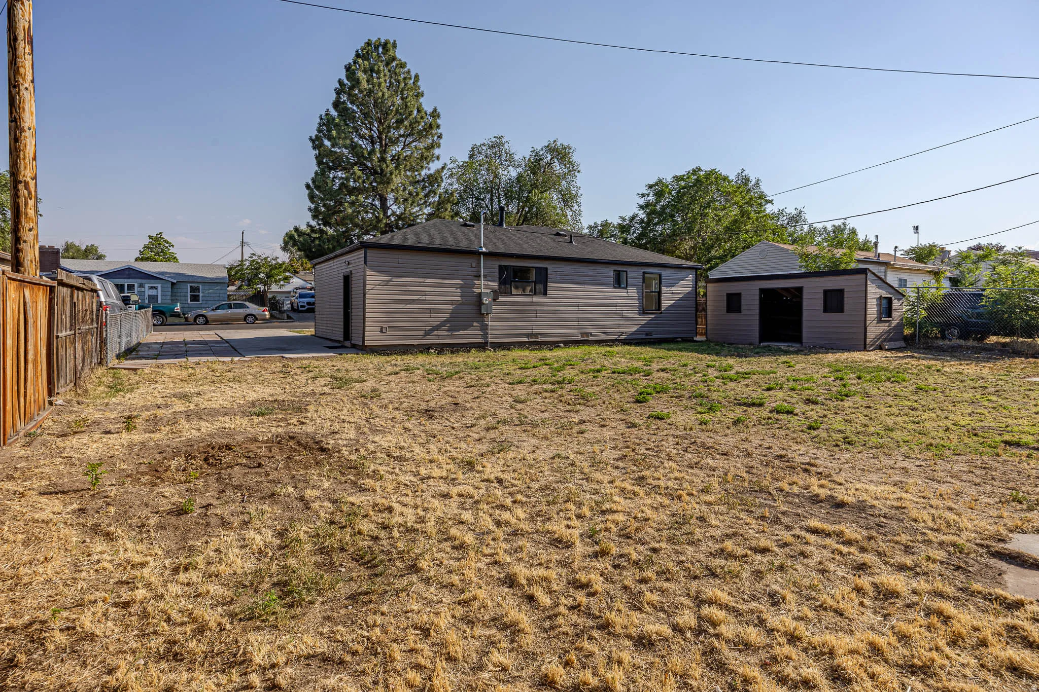 Expansive backyard featuring a detached accessory building, wood fence, and mature trees
