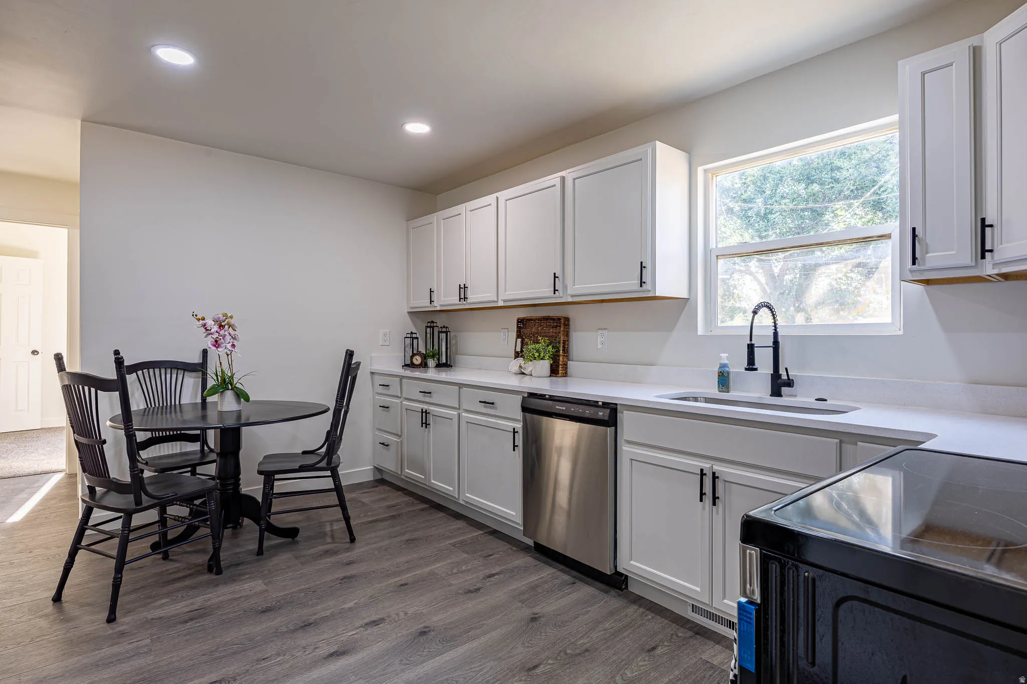 Kitchen featuring white cabinetry, light-toned countertops, and wood-finish flooring