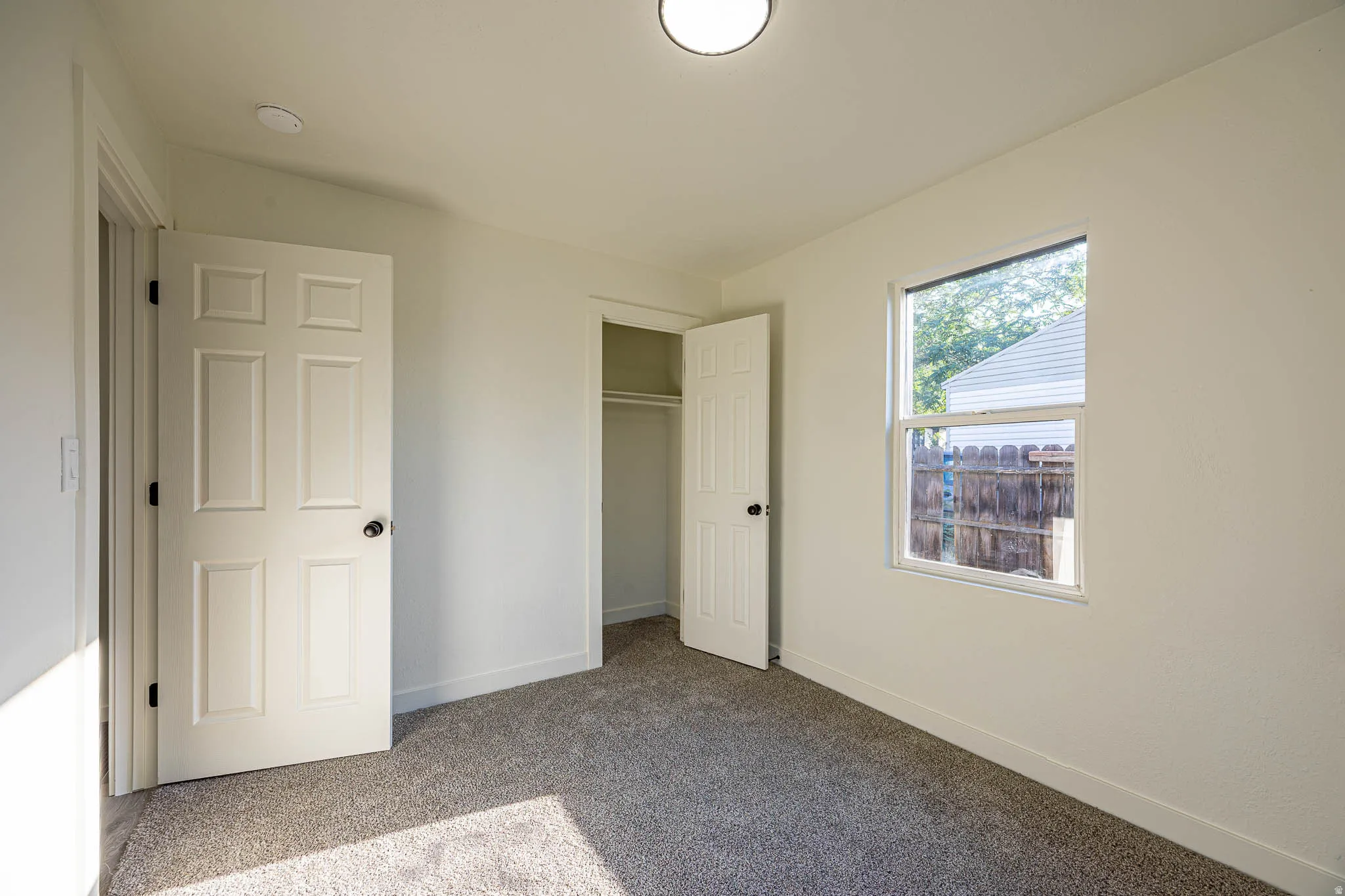 Neutral interior featuring light-colored walls and grey carpet flooring