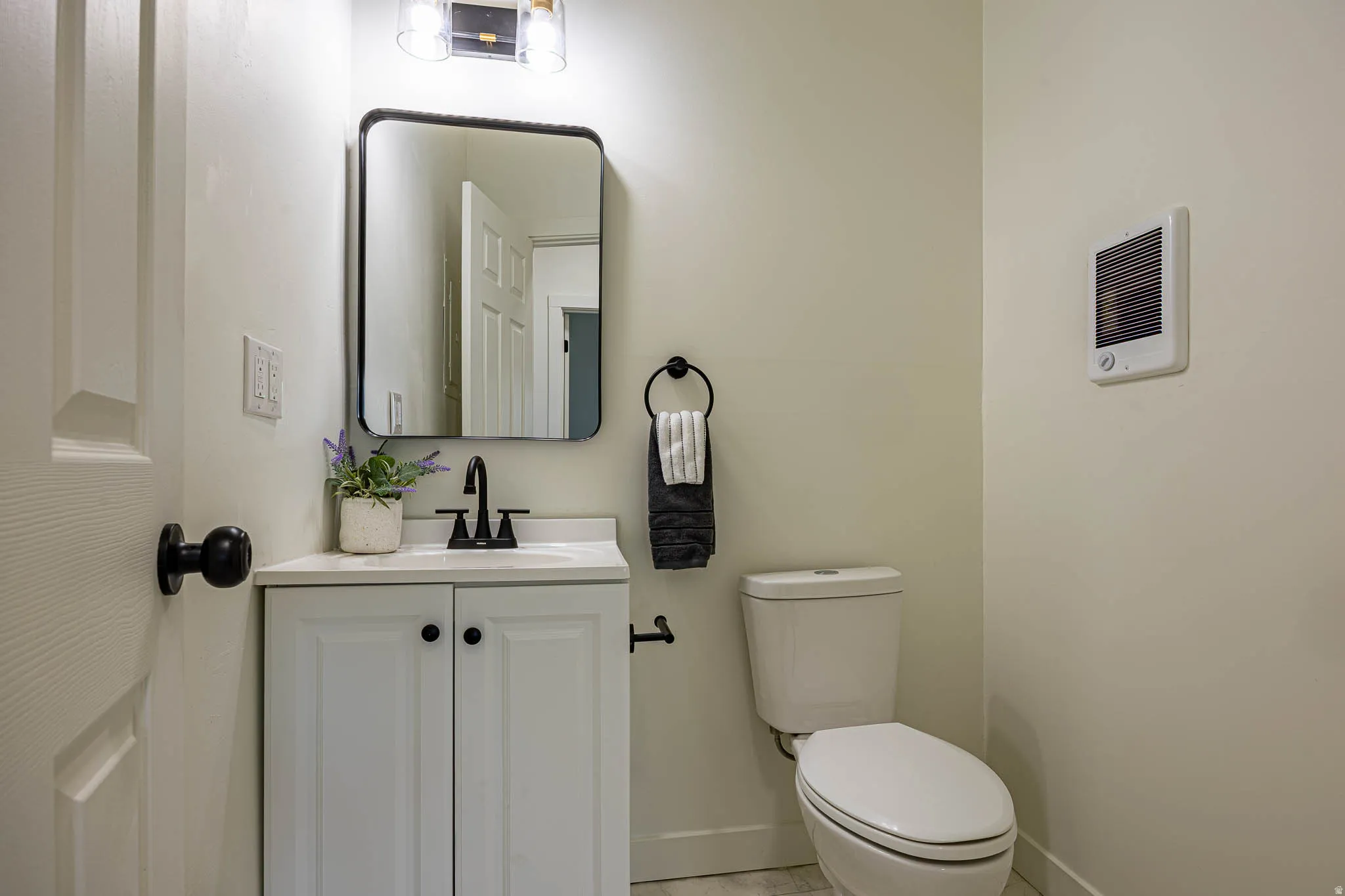 Bathroom featuring a white vanity with panel-front cabinetry, a white countertop, and a black faucet