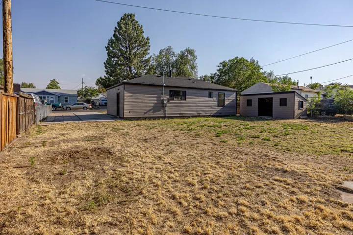 Expansive backyard featuring a detached accessory building, wood fence, and mature trees