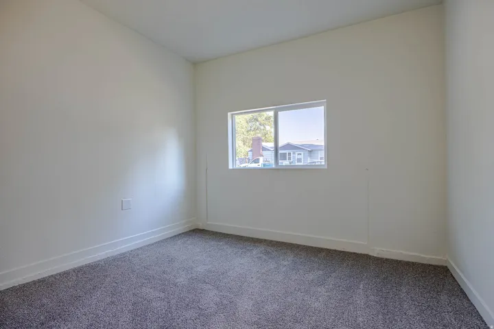 Light-filled interior space featuring neutral wall tones, white baseboards, and gray textured carpeting