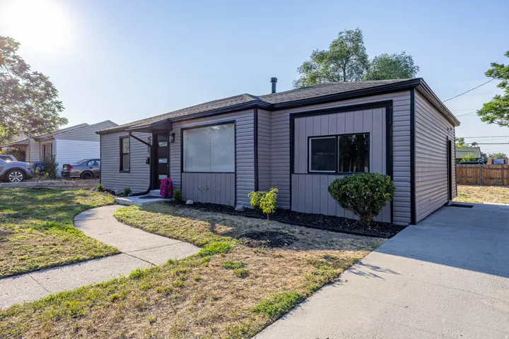 Single-story residence featuring light gray siding with dark trim, a covered front entry, a concrete walkway, and a concrete driveway