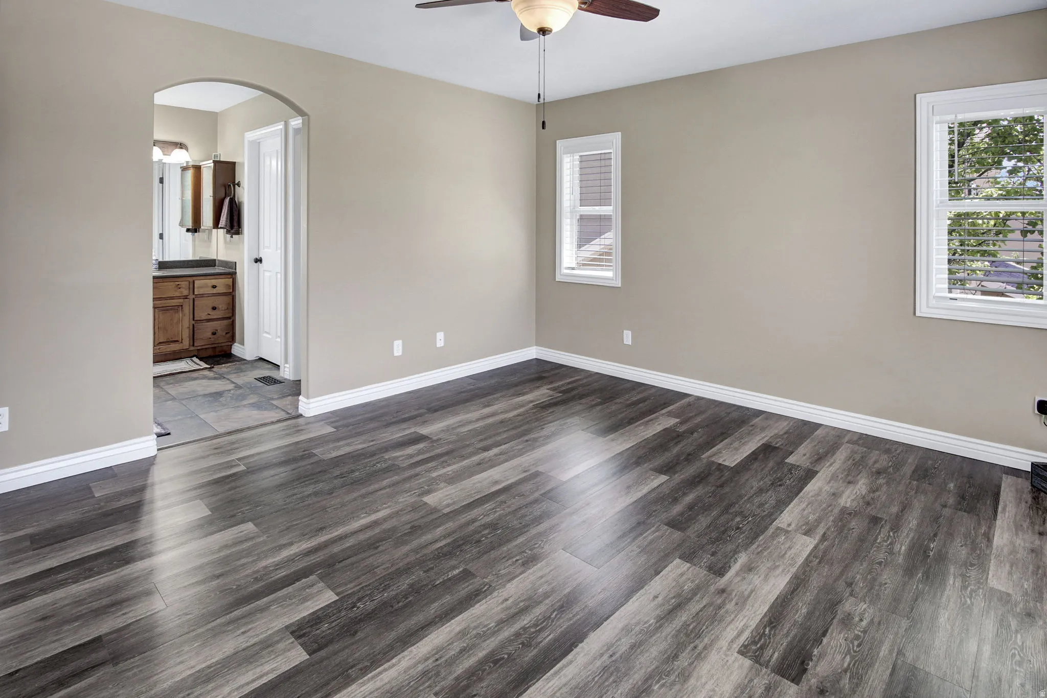 Spacious room featuring wood-finish flooring and two windows with blinds