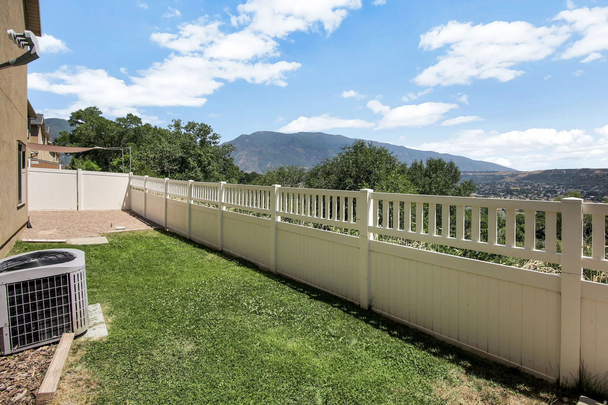 Expansive green lawn featuring a white privacy fence