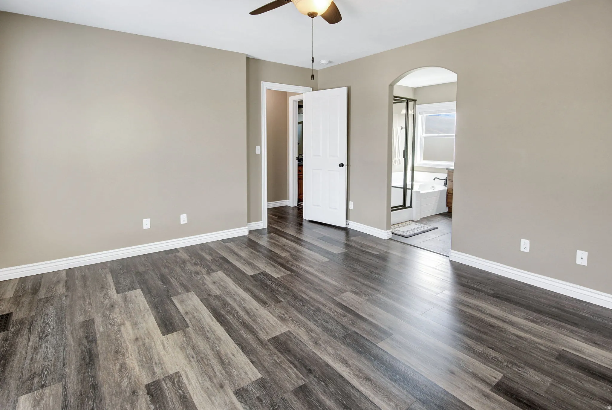 Spacious room featuring wood-finish flooring, neutral wall paint, and white baseboards