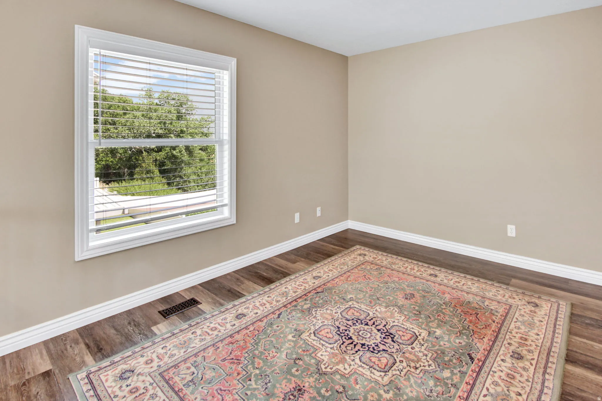 Bright room featuring light beige walls and wood-finish flooring
