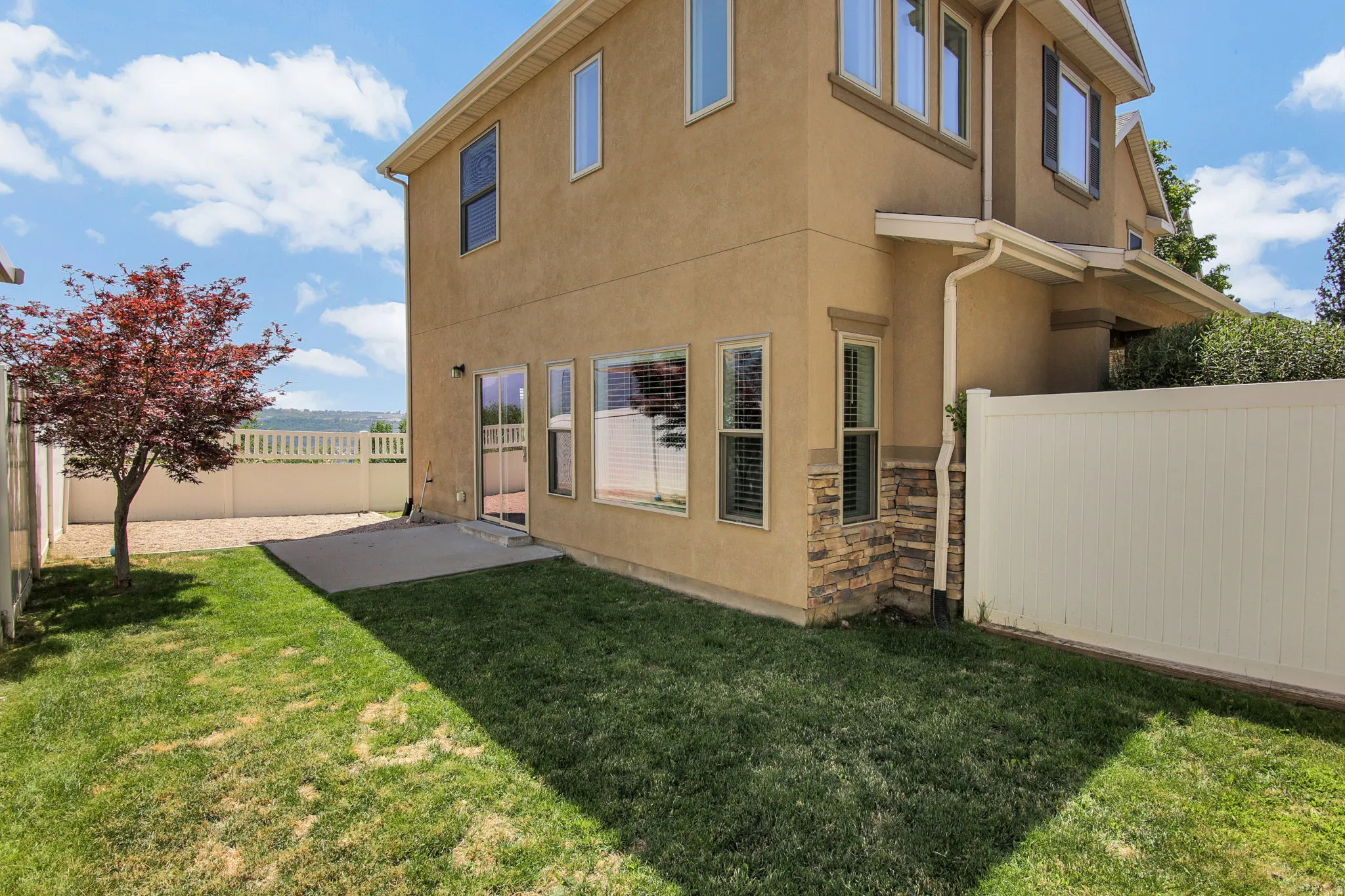 Stucco-clad exterior featuring stacked stone accents and multiple large windows with blinds