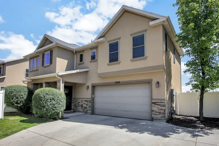 Stucco exterior featuring a two-car garage, stone veneer accents, and a covered front entry