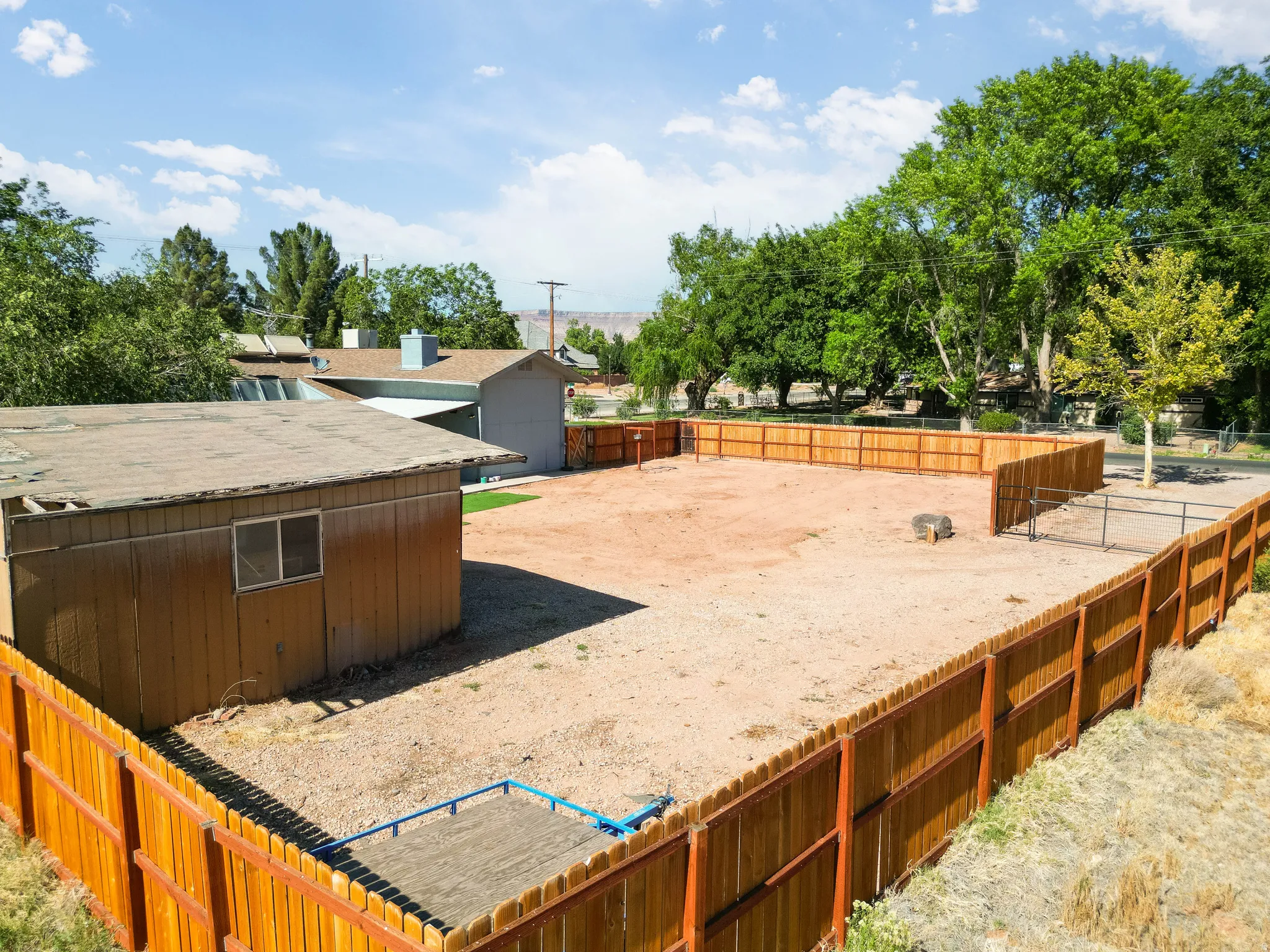 Expansive outdoor space featuring a new wood privacy fence, a detached shed, a gravel ground cover, and a patch of artificial turf