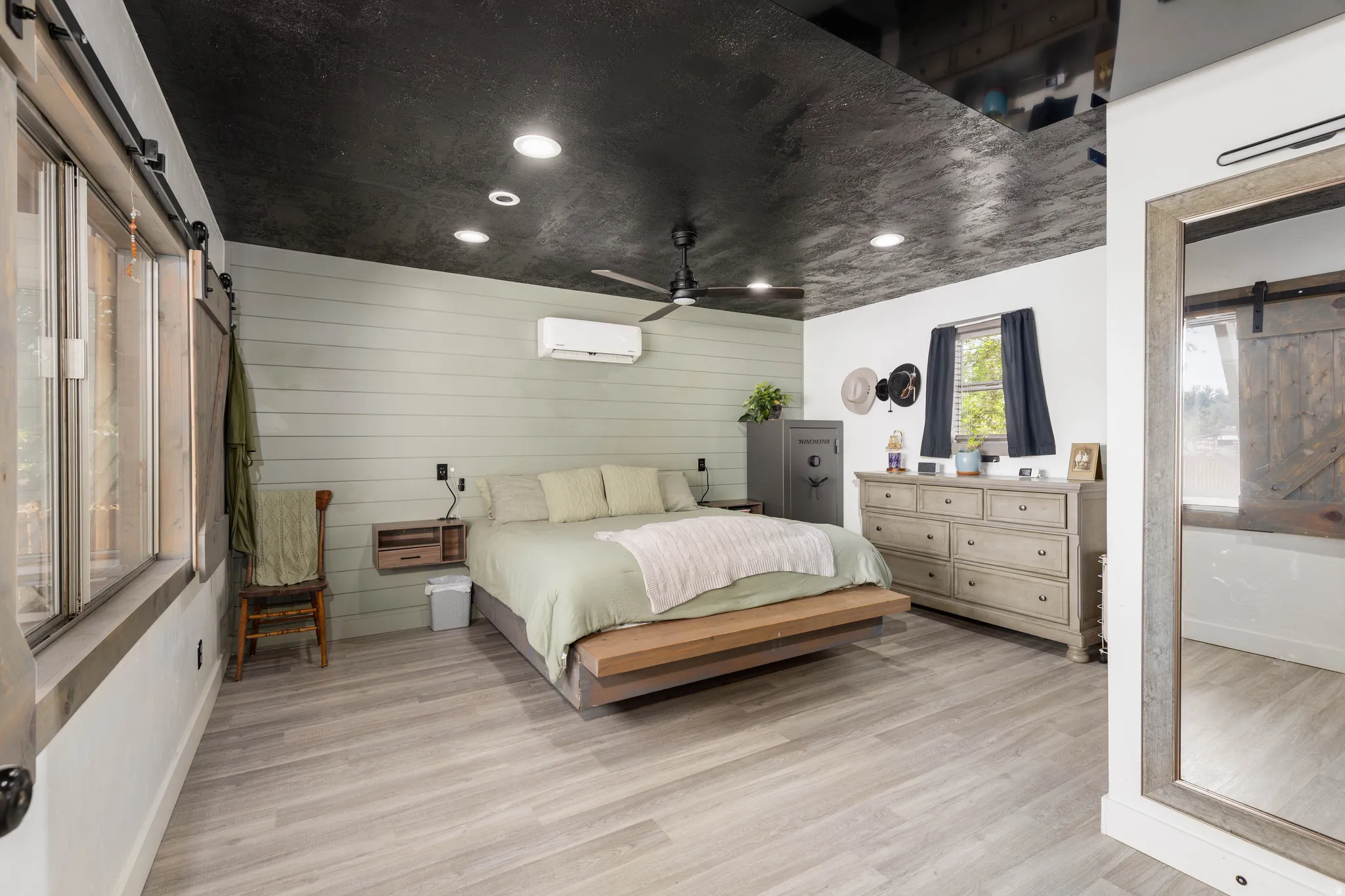 Spacious room featuring wood-finish flooring, a textured black ceiling with recessed lighting, and a ceiling fan