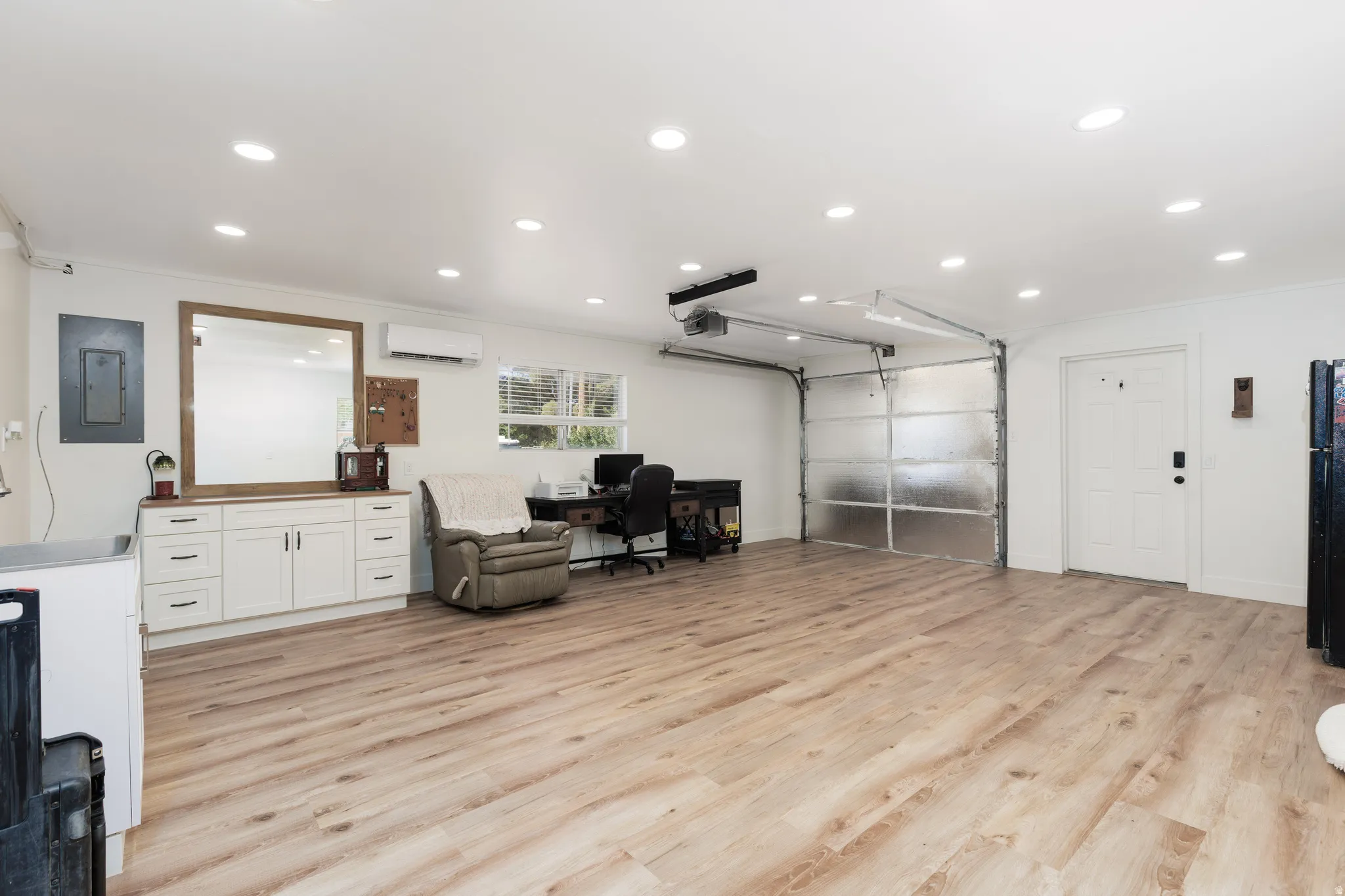 Spacious interior featuring wood-finish flooring, recessed lighting, and a frosted panel garage door
