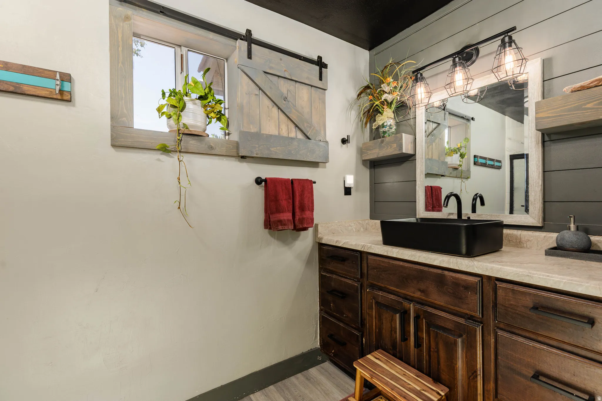Bathroom featuring a dark wood vanity with ample storage, a black vessel sink with a matching matte black faucet, and a large framed mirror