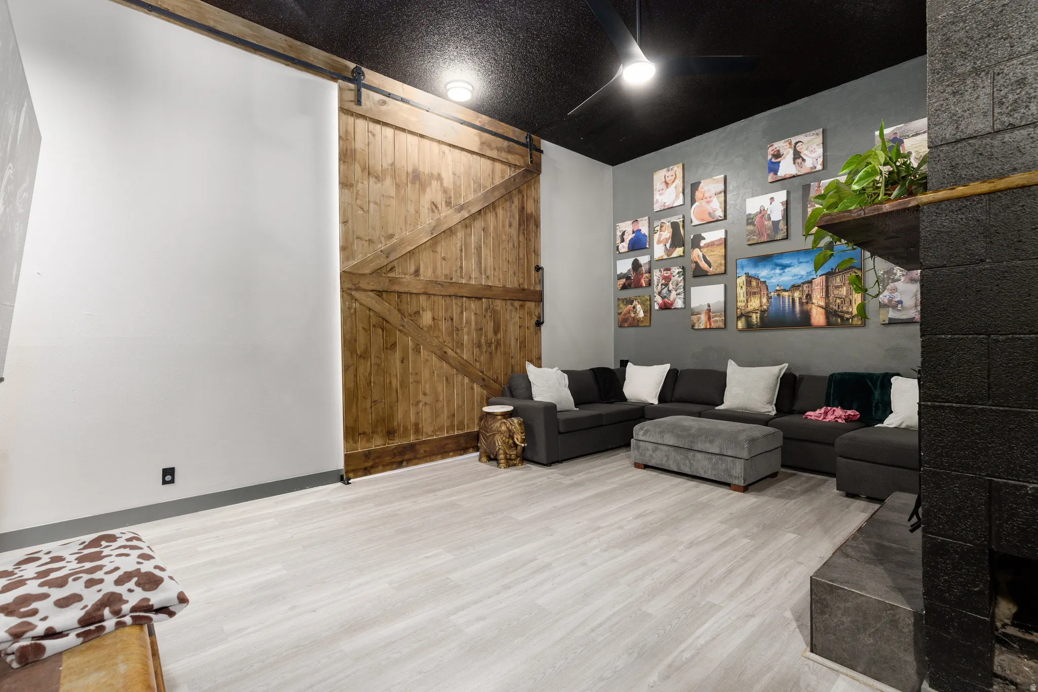 Spacious room featuring light wood-finish flooring, a dark accent wall, and a textured black ceiling