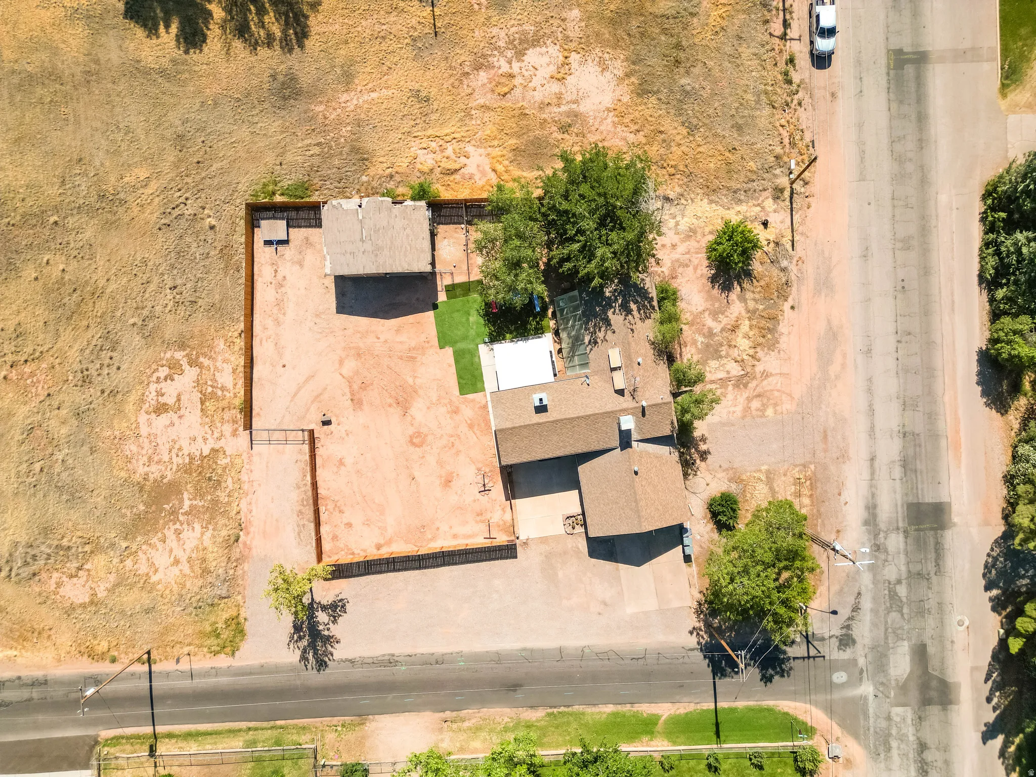 Expansive property featuring a main residence with a brown shingle roof, a secondary structure, a fenced perimeter, and a section of artificial turf