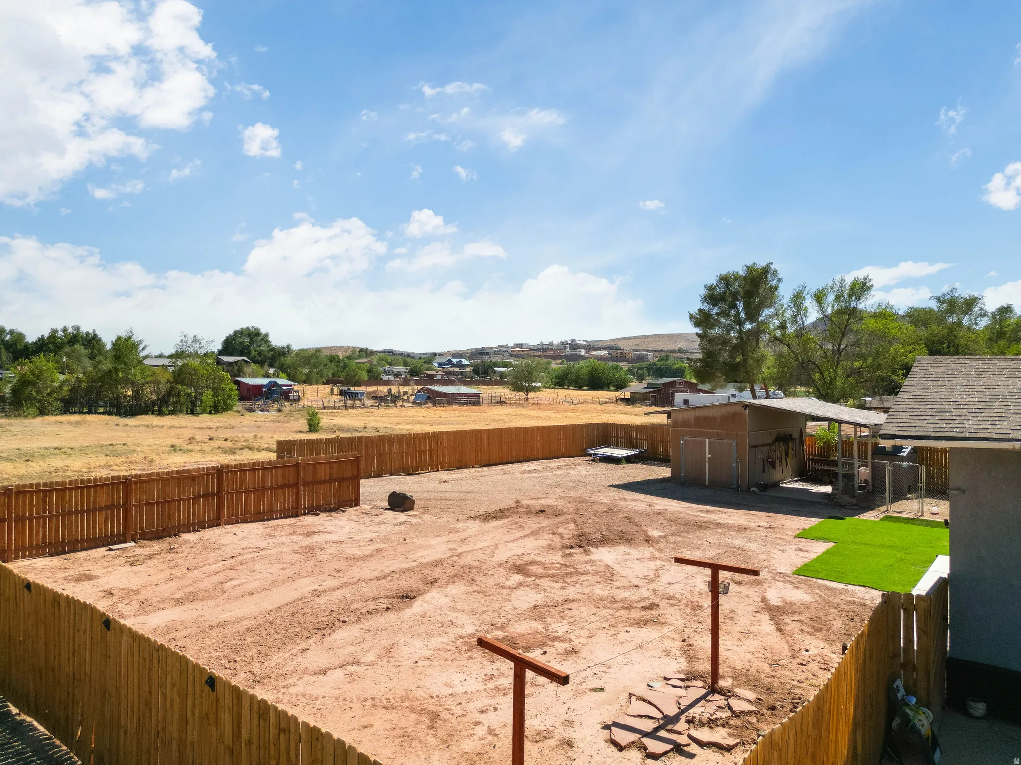 Large, fully fenced backyard with a newly installed wood privacy fence, featuring a covered outbuilding and a section of artificial turf