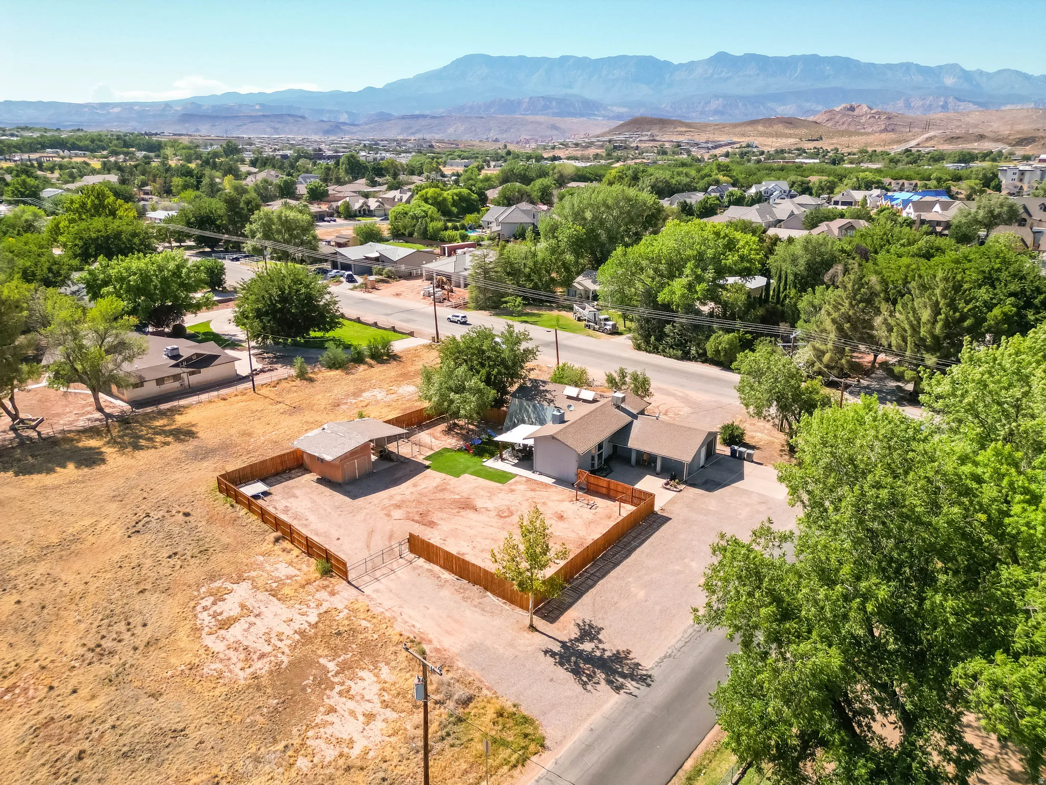 Aerial perspective showcasing a single-story residence with an attached garage, a separate outbuilding, and a fenced yard