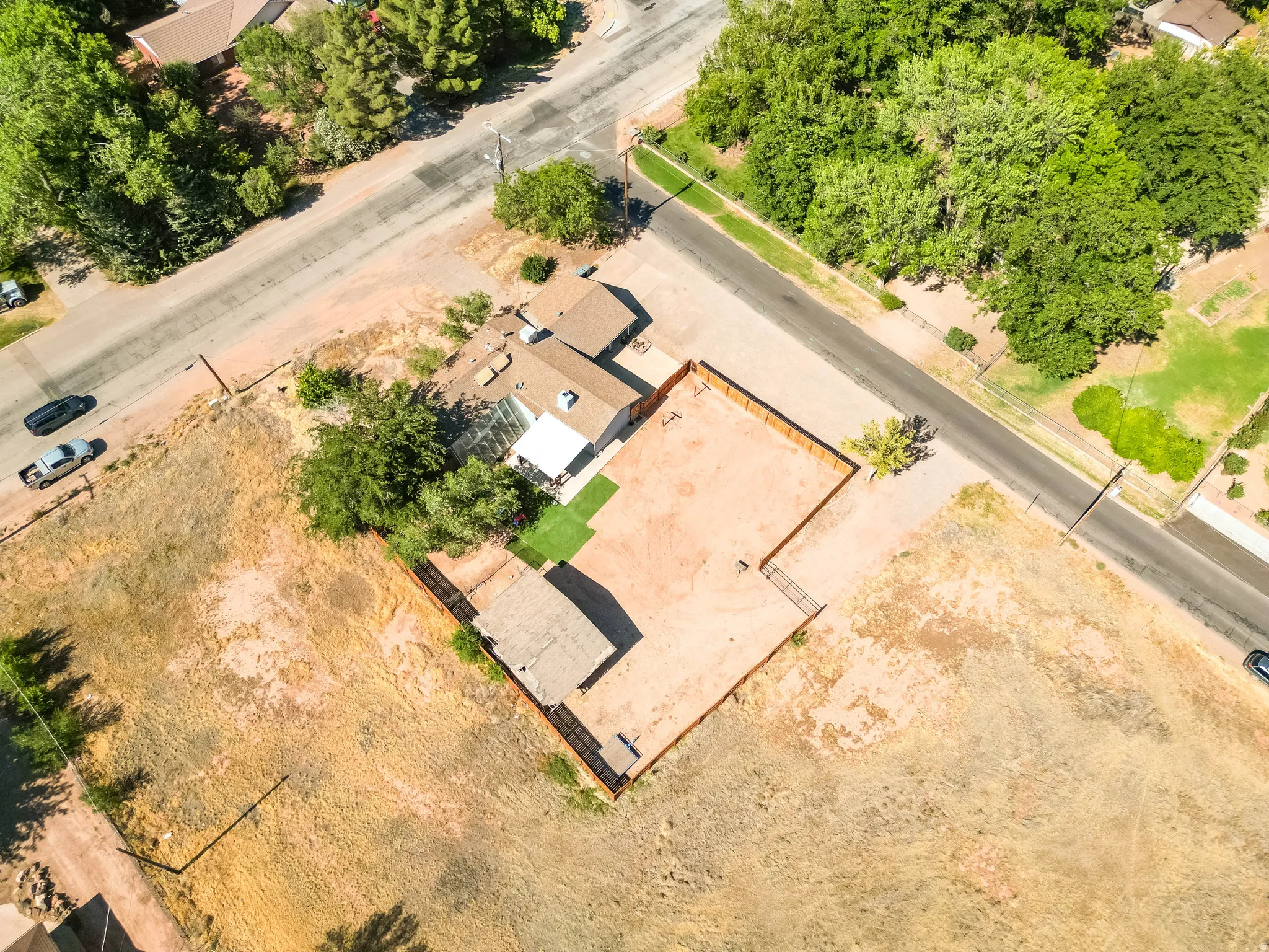Expansive corner lot featuring a detached residential structure, fenced perimeter, and street frontage on two sides