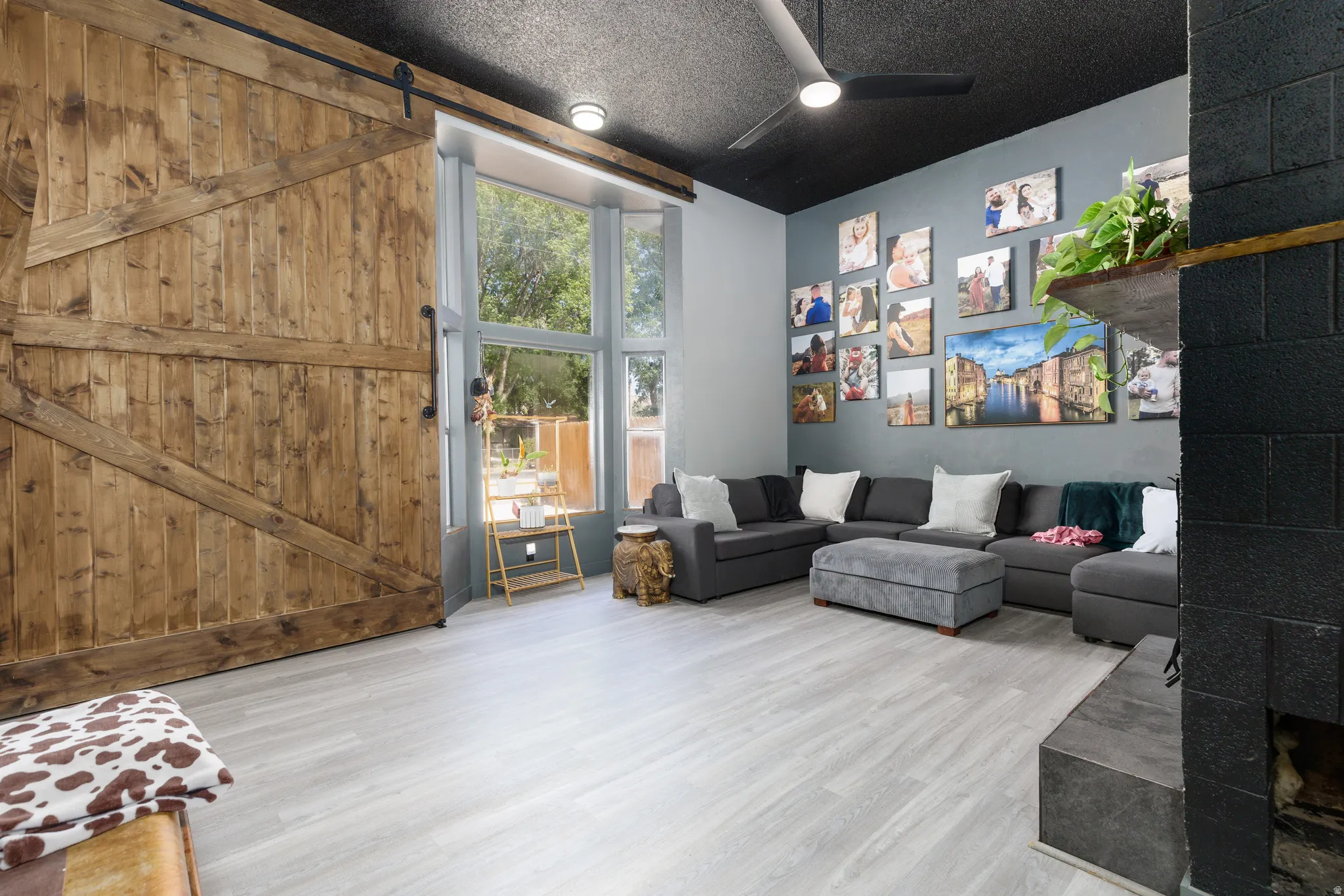 Spacious living area featuring a large wooden barn door, light wood-finish flooring, and a floor-to-ceiling window